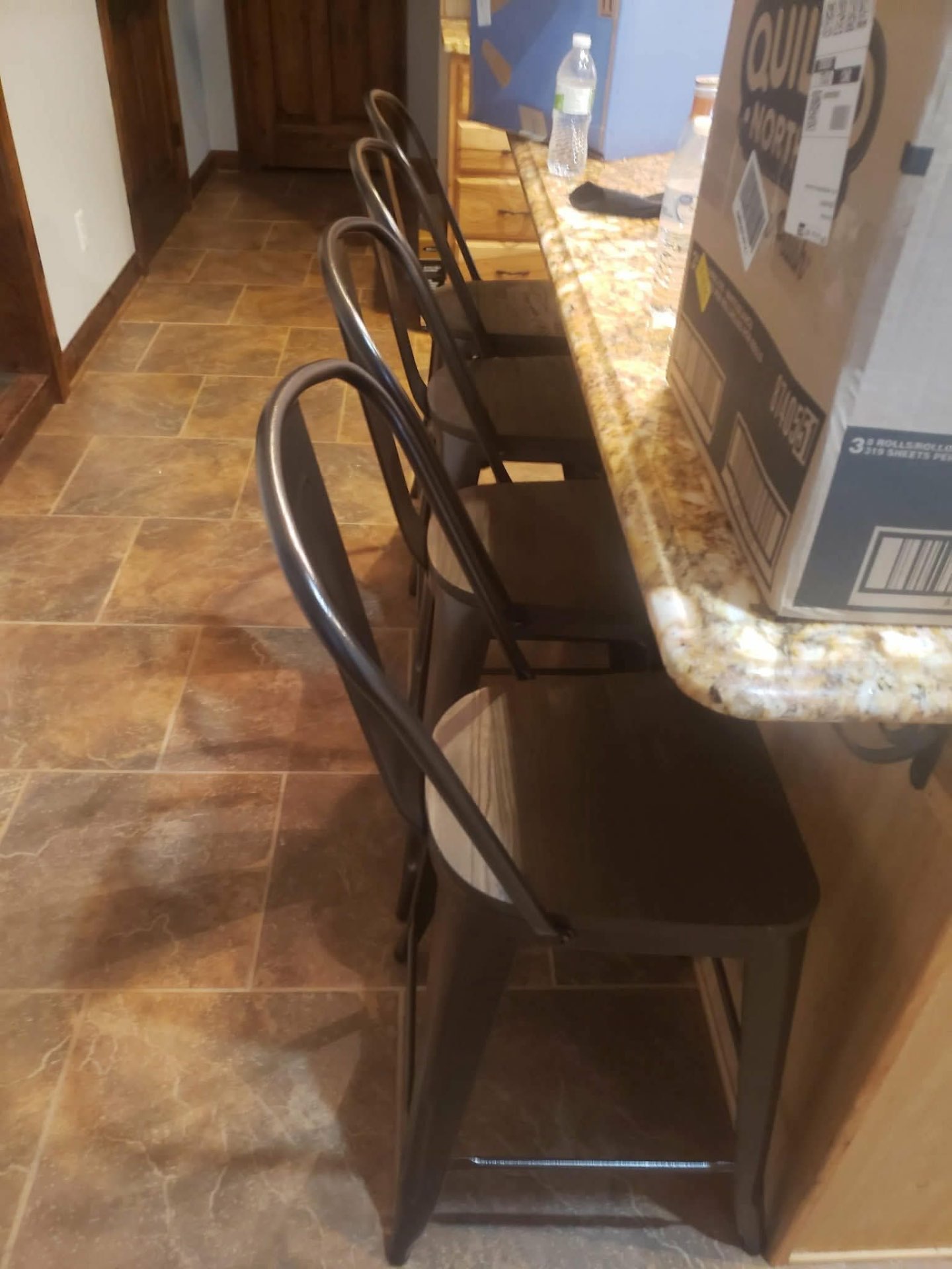 Assembled metal and wood counter stools at a granite bar