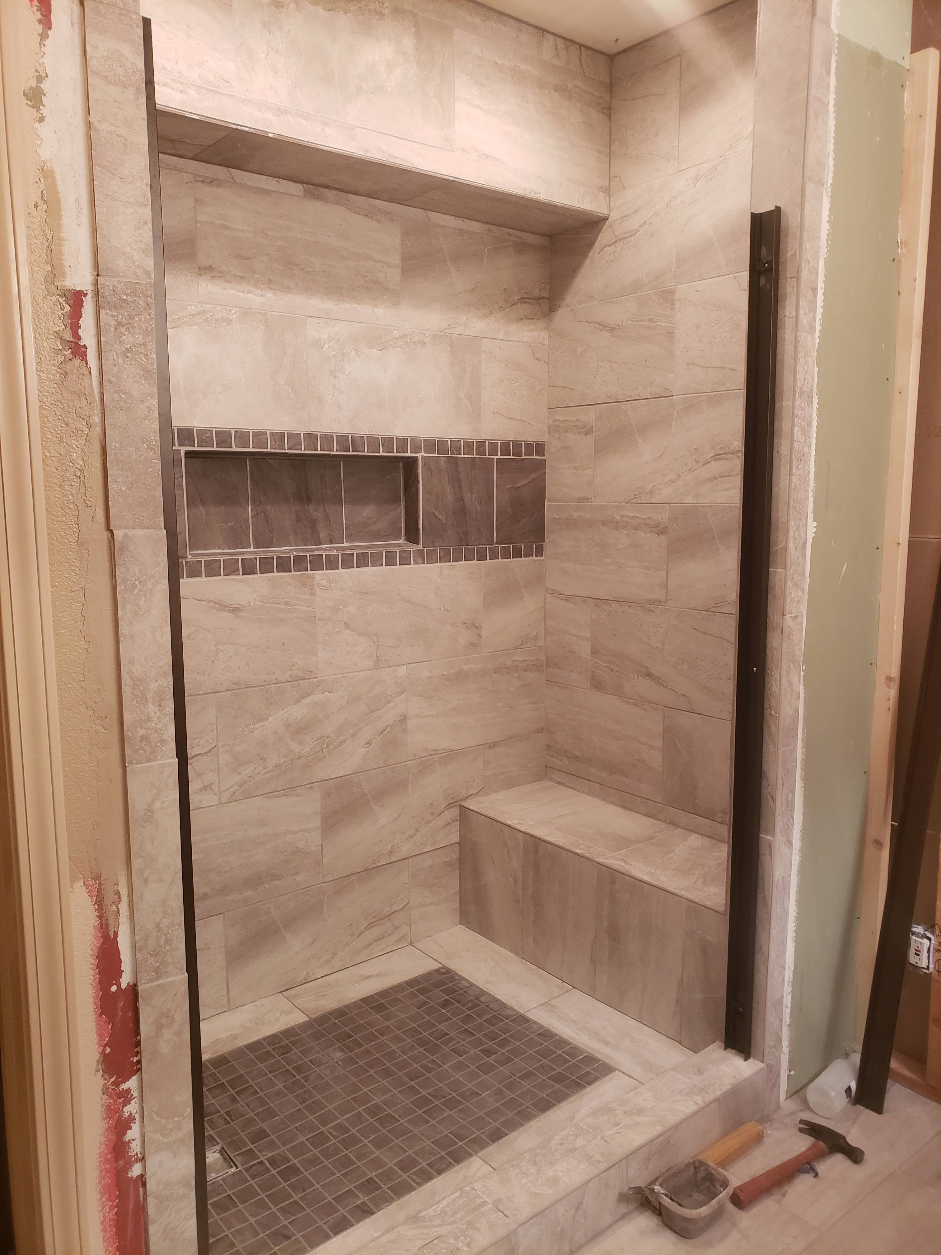 Marble-look tile shower with mosaic niche